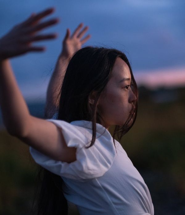 Person stretching gently outdoors with a serene natural background.